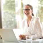 Laughing businesswoman working in office with laptop